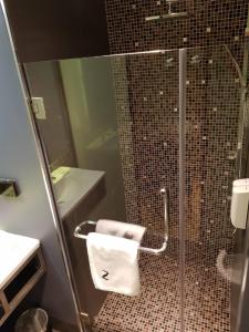 a bathroom with a shower with a toilet paper holder at Bizotel Premier Hotel & Residence in Bangkok