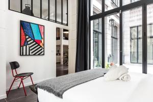 - une chambre avec un grand lit blanc et une chaise dans l'établissement Outstanding Artist Loft - Between Marais and Canal, à Paris