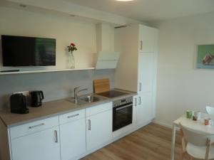 uma cozinha com armários brancos, um lavatório e uma televisão em Auszeit em Bell