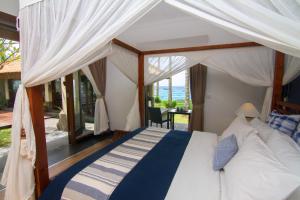 a bedroom with a canopy bed and a balcony at Villa Anjani - Ocean view Villa, With Private Garden and Cook - Candidasa in Candidasa