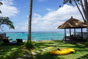 a beach with a gazebo and a yellow kayak on the grass at Villa Anjani - Ocean view Villa, With Private Garden and Cook - Candidasa in Candidasa