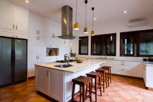 a kitchen with white cabinets and a kitchen island with bar stools at Villa Anjani - Ocean view Villa, With Private Garden and Cook - Candidasa in Candidasa +29 photos