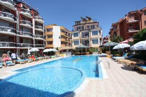 a swimming pool with chairs and umbrellas next to some buildings at Salena Beach Hotel in Primorsko