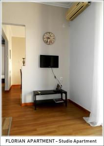 a living room with a table and a clock on the wall at Florian Flat Complex in Preveza