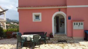 a table and chairs in front of a pink building at Apartments Aleksandra in Rab