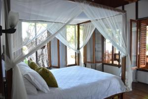 a bedroom with a white canopy bed with a window at Bobocha Siladen Boutique Resort in Bunaken