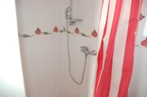 una ducha con cortina de ducha de rayas rojas y blancas en Hotelik Za Murem, en Kołobrzeg