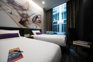 two beds in a hotel room with a painting on the wall at V Hotel Lavender in Singapore