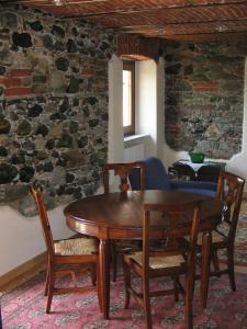 een houten tafel en stoelen in een kamer met een stenen muur bij La Miseria in Ovada