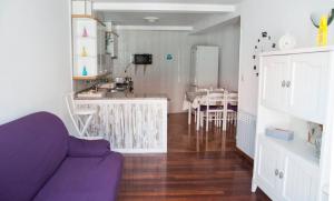 sala de estar con sofá púrpura y cocina en Casa Ledicia, en Castro Caldelas