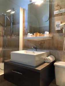a bathroom with a white sink and a toilet at Logis Hôtel-Restaurant Le Commerce in Rieupeyroux +28 photos