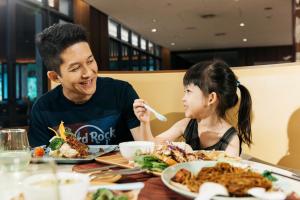 a man and a little girl sitting at a table eating food at Hard Rock Hotel Desaru Coast in Desaru