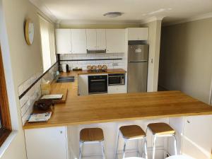 a kitchen with a counter with stools in it at Wallis View 13 in Forster