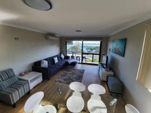 a living room with a couch and a table and chairs at Wallis View 13 in Forster