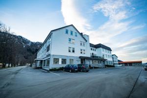 un grand bâtiment blanc avec des voitures garées dans un parking dans l'établissement Nordfjord Hotell - Bryggen, à Nordfjordeid