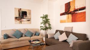 ein Wohnzimmer mit 2 Sofas und Gemälden an der Wand in der Unterkunft Heima Puerta del Sol - Opera Center in Madrid