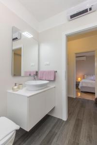 ein weißes Badezimmer mit einem Waschbecken und einem Spiegel in der Unterkunft Villa Jozica in Murter