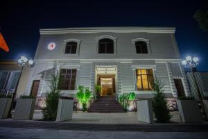 una casa blanca por la noche con un reloj en ella en Amina hotel, en Samarkand