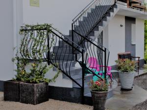 eine schmiedeeiserne Treppe mit Topfpflanzen neben einem Haus in der Unterkunft côté chêne in Puycornet