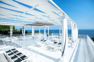 taras z białymi stołami i krzesłami oraz oceanem w obiekcie Bianco Olympico Beach Resort-All Inclusive w mieście Vatopedi