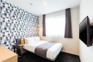 a hotel room with a bed and a television at M's Hotel Gojo Odawara in Kyoto
