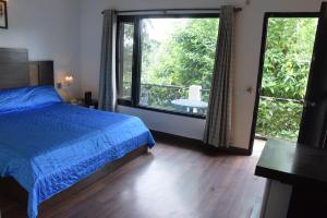 ein Schlafzimmer mit einem Bett und einem großen Fenster in der Unterkunft The Pine Crest Resort Bhimtal in Bhīm Tāl