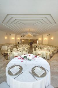 Hotel Bel Sit في Comerio: قاعة احتفالات كبيرة مع طاولات وكراسي بيضاء