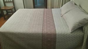 a bed with a comforter and pillows on it at Hostal Fisterra in Lugo