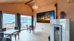 ein Wohnzimmer mit einem TV, einem Tisch und Stühlen in der Unterkunft alpen select lodge Kleinwalsertal in Riezlern