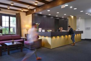 a man standing at a counter in an office lobby at relexa Waldhotel Schatten Stuttgart in Stuttgart