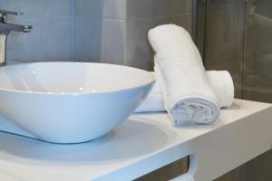 a white sink and roll of toilet paper on a counter at GHT S'Agaró Mar Hotel in Sant Feliu de Guíxols