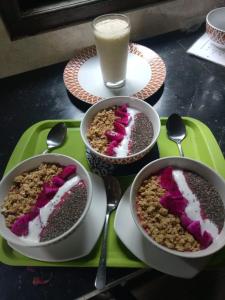 una mesa con tres tazones de postres y un vaso de leche en Jasri Dalem Surf Retreat en Jasri