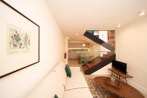 a living room with a white couch and a staircase at Apartamentos Habitavit en Cáceres in Cáceres