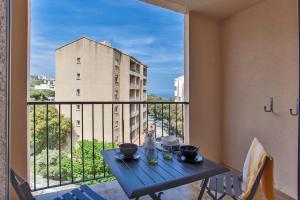 - une table sur un balcon avec vue sur un bâtiment dans l'établissement Offre Spécial Bastia Proche Centre Parking, à Bastia