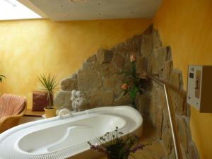 Xundheits Hotel Garni Eckershof في باد بيرنباخ: حوض استحمام في غرفة بجدار حجري