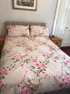 a bed with pink flowers on a white comforter at Garden Double Room with own door access and bathroom in Rostrevor