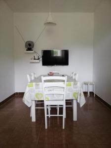 mesa de comedor con sillas blancas y TV de pantalla plana en Charming house Tonći, en Lovište