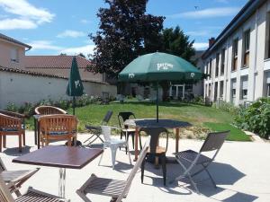 a patio with tables and chairs and a green umbrella at MOODz HOTEL VIENNE in Pont-Évêque