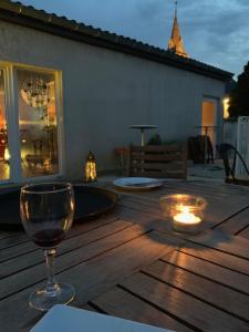 a wine glass sitting on a wooden table with a candle at MOODz HOTEL VIENNE in Pont-Évêque