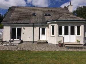 a white house with white doors and a patio at The Willows in Dalchreichart