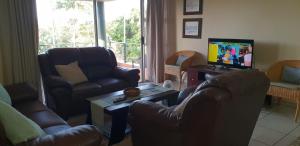 a living room with two leather chairs and a television at Ramsgate Palms Unit 20 in Ramsgate