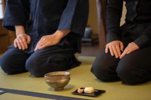 un grupo de personas sentadas en el suelo haciendo yoga orativo en 伝心庵 Garden Villa Denshin-An, en Kioto