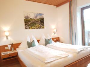Schlafzimmer mit einem Bett mit weißer Bettwäsche und blauen Kissen in der Unterkunft Apartments Haus Huber in Mühlbach am Hochkönig
