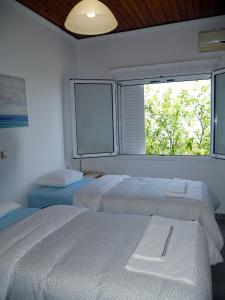 two beds in a room with a window at Moraitika Old Village Apartments in Moraitika