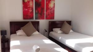 2 Betten in einem Zimmer mit Gemälden an der Wand in der Unterkunft Villa A50 in Negombo