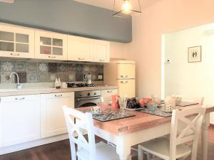 una cucina con tavolo in legno e una cucina con armadietti bianchi di THE BLUE LODGE-cozy flat close to Piazza del Campo a Siena