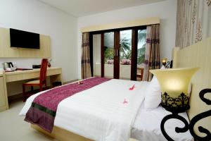 a bedroom with a bed and a desk and a window at Puri Saron Senggigi Hotel in Senggigi