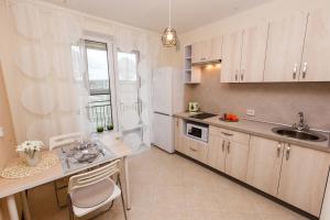 a kitchen with white cabinets and a sink and a table at Атмосферная квартира в Кошелев парке in Dubovyy Gay