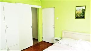 1 dormitorio con cama blanca y paredes verdes en Alex's Apartman & Panzió, en Hajdúszoboszló