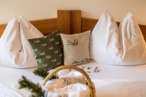 a bed with three pillows and a basket on it at Bar Garni Reischnhitt des Eschgfeller Christoph in Sarntal